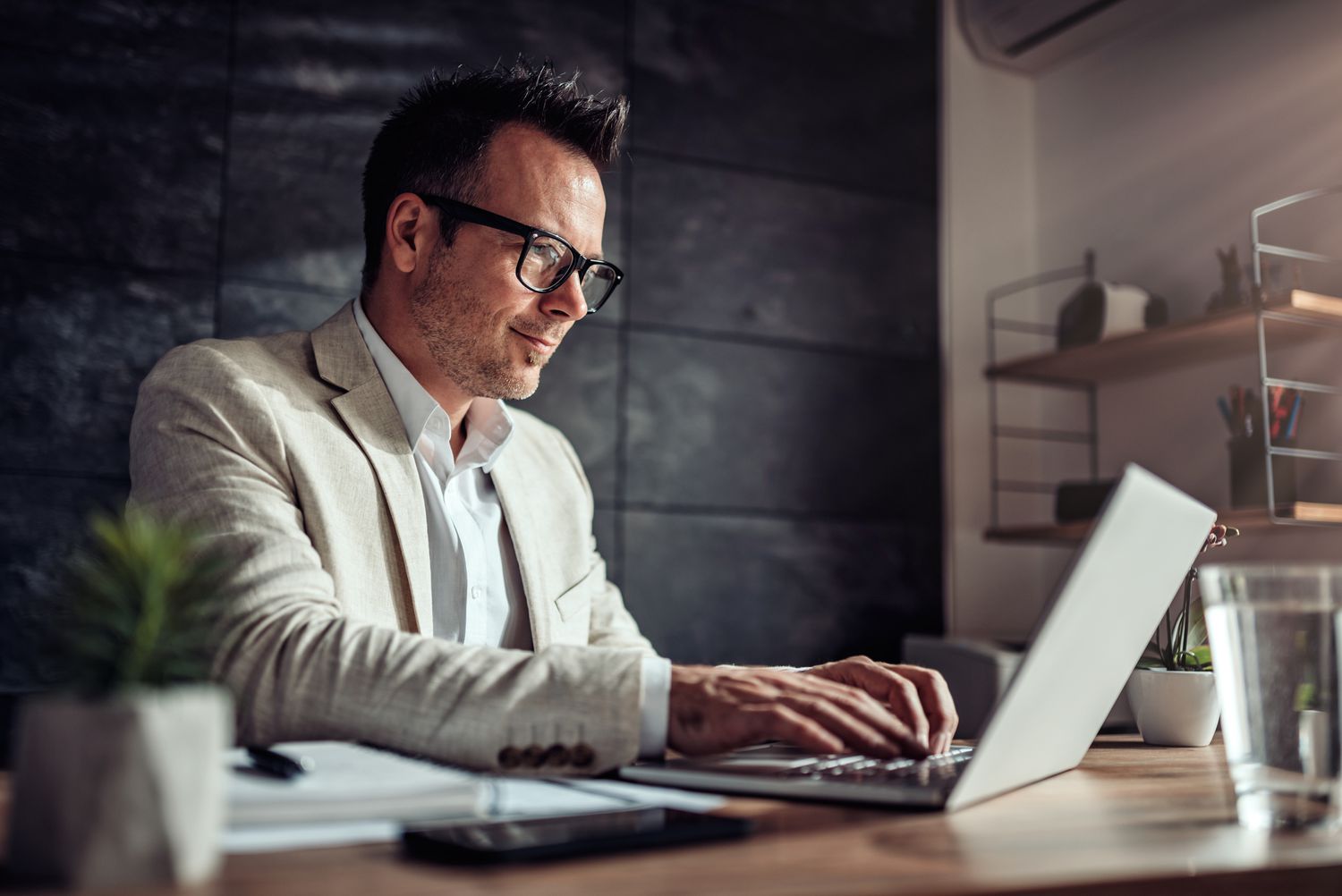 a man in a suit working on his desk on a laptop