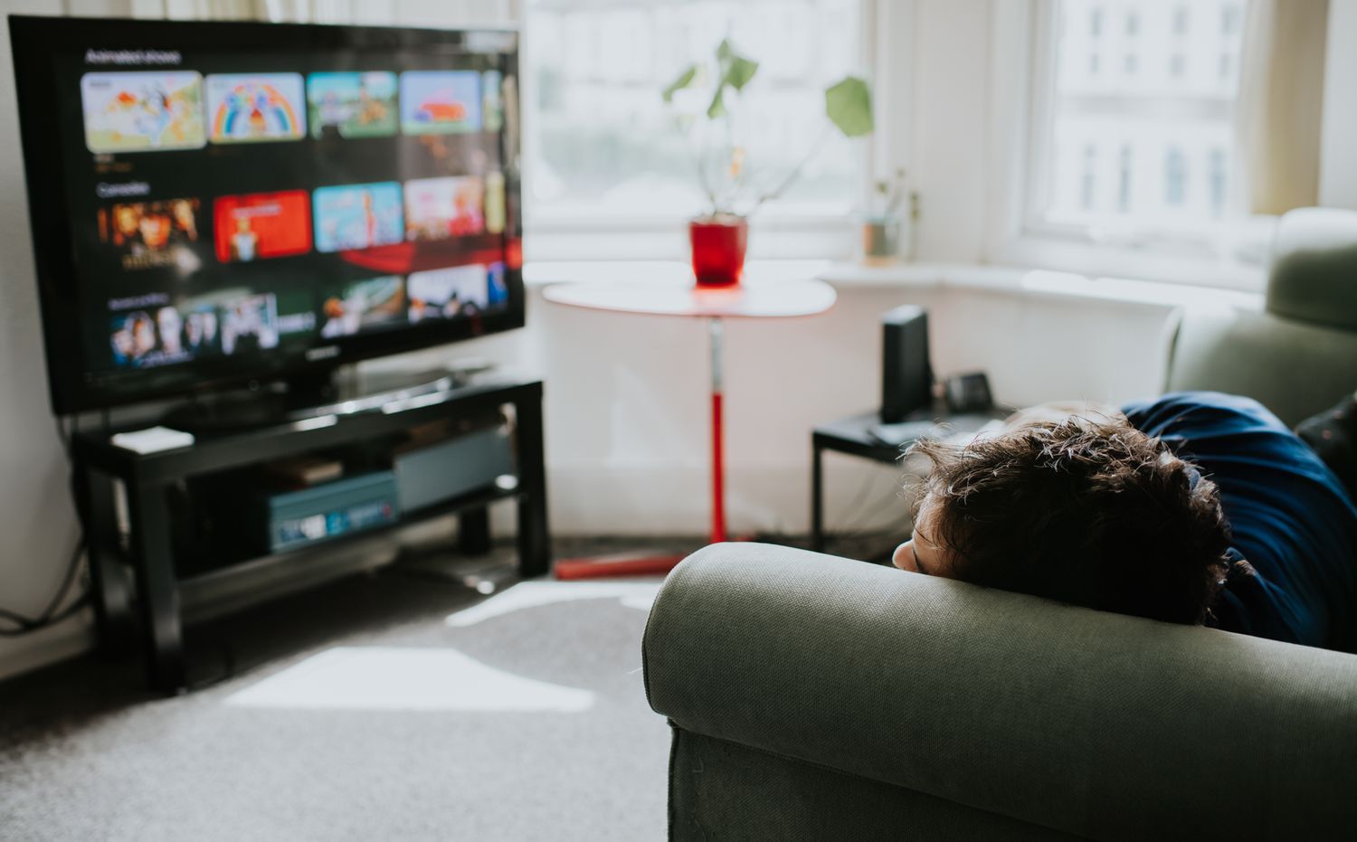 Man rests on the couch and considers what to stream.