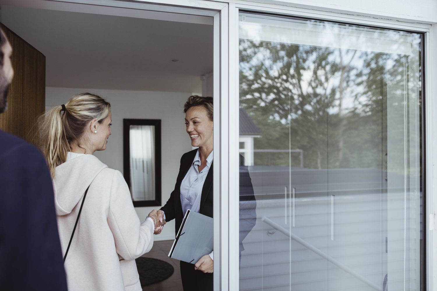 Two women shake hands inside a home.