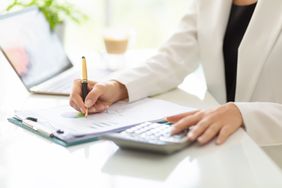 Businesswoman working with business document, calculator, and laptop on table