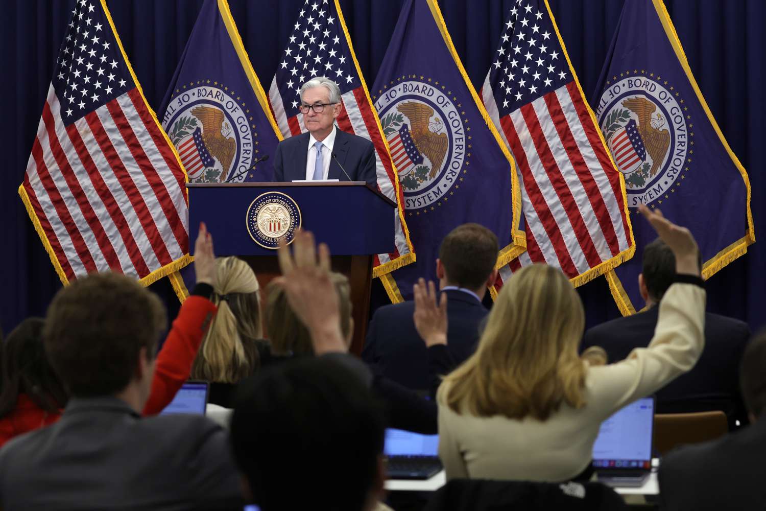 Jerome Powell standing at a podium at a press conference