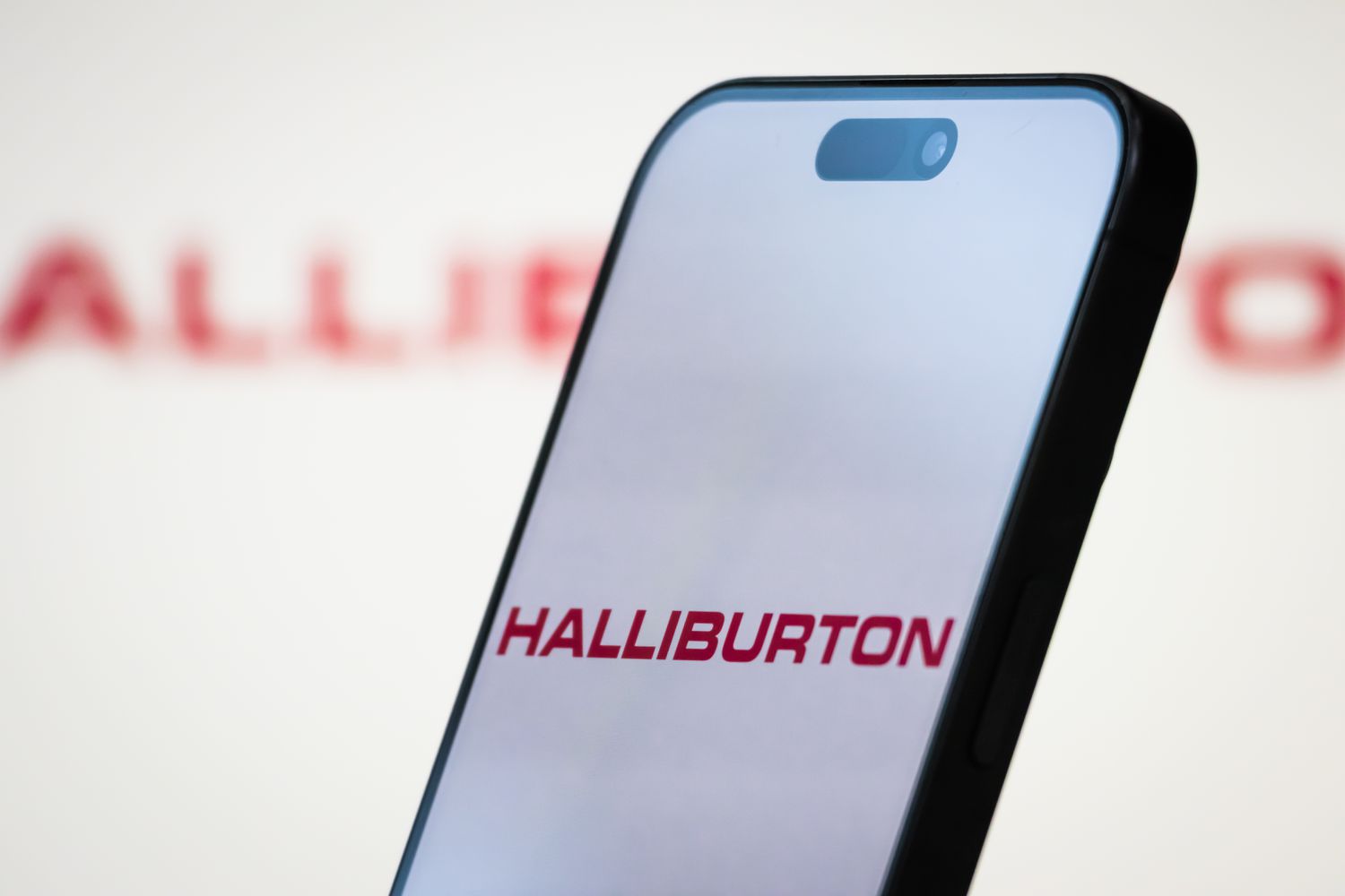 Logo of Halliburton Company is displayed on a smartphone screen, with the company's branding in the background