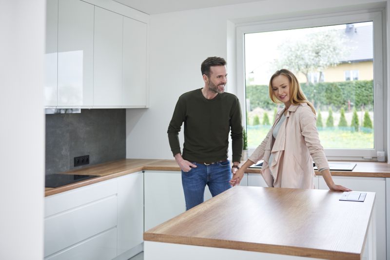 A man and a woman stand in a kitchen of a new house