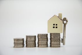 Stacks of coins with a house and key on top