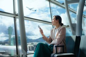 Person checking prices on a cell phone in an airport.