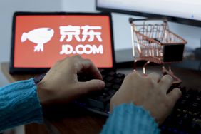 A person types next to the JD.com logo displayed on the screen of a tablet