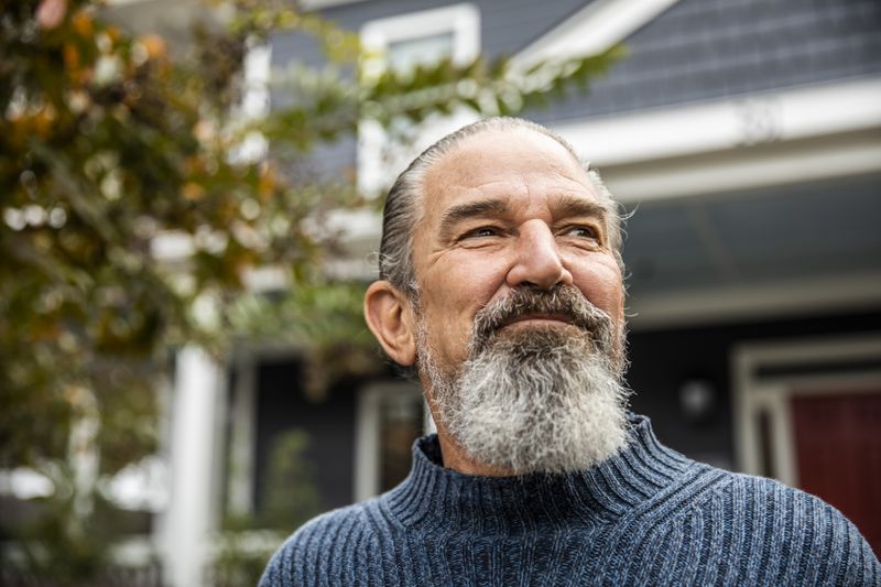 Portrait of senior man in front of suburban home