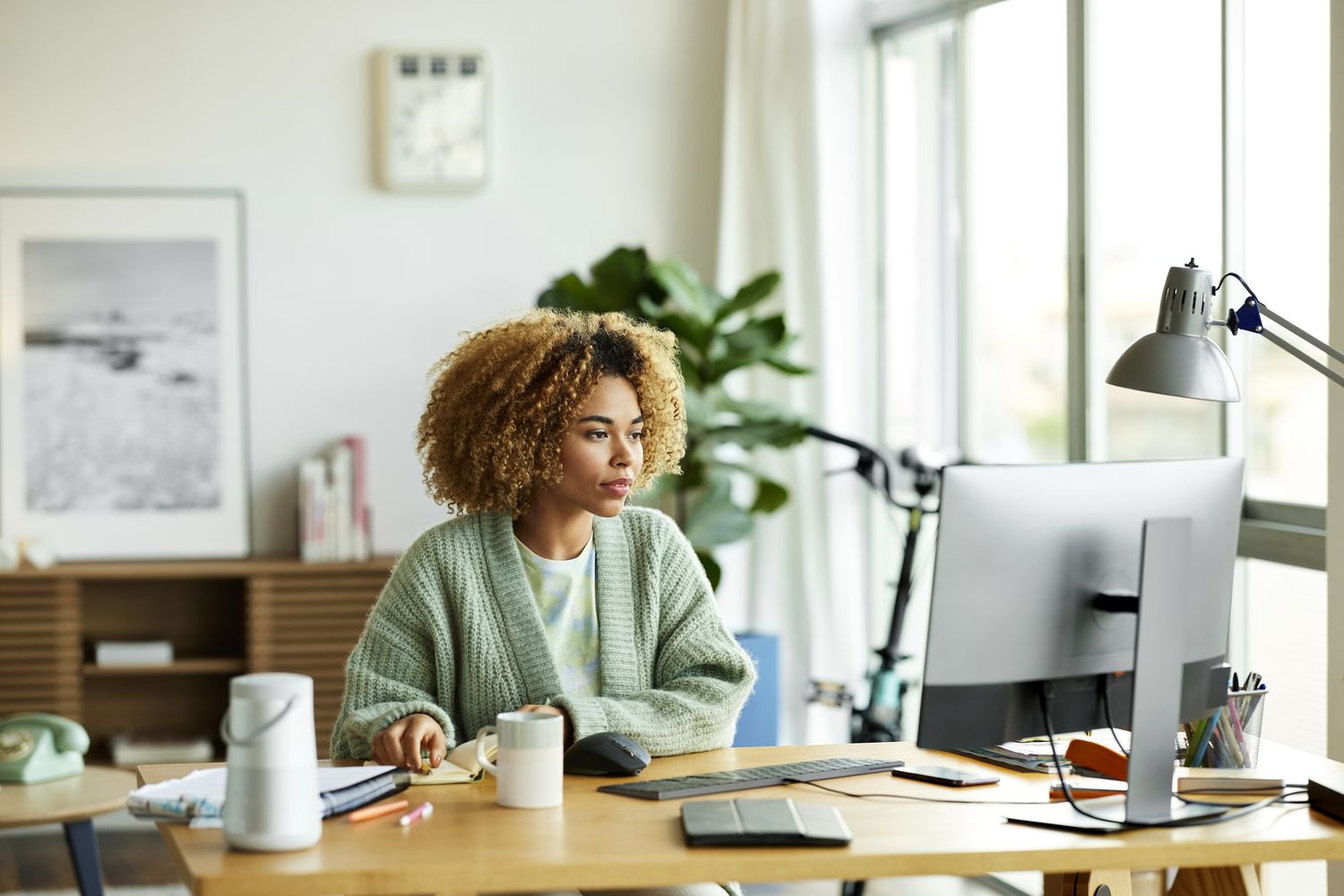A woman works at a desktop computer in her home office.