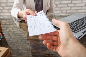 Businesswoman Giving Cheque To Her Colleague
