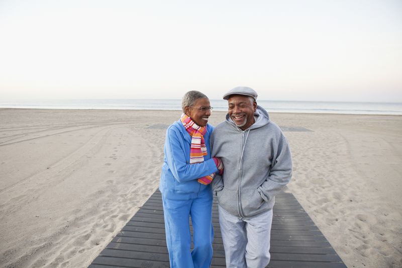 Senior couple walking together arm in arm on a beach