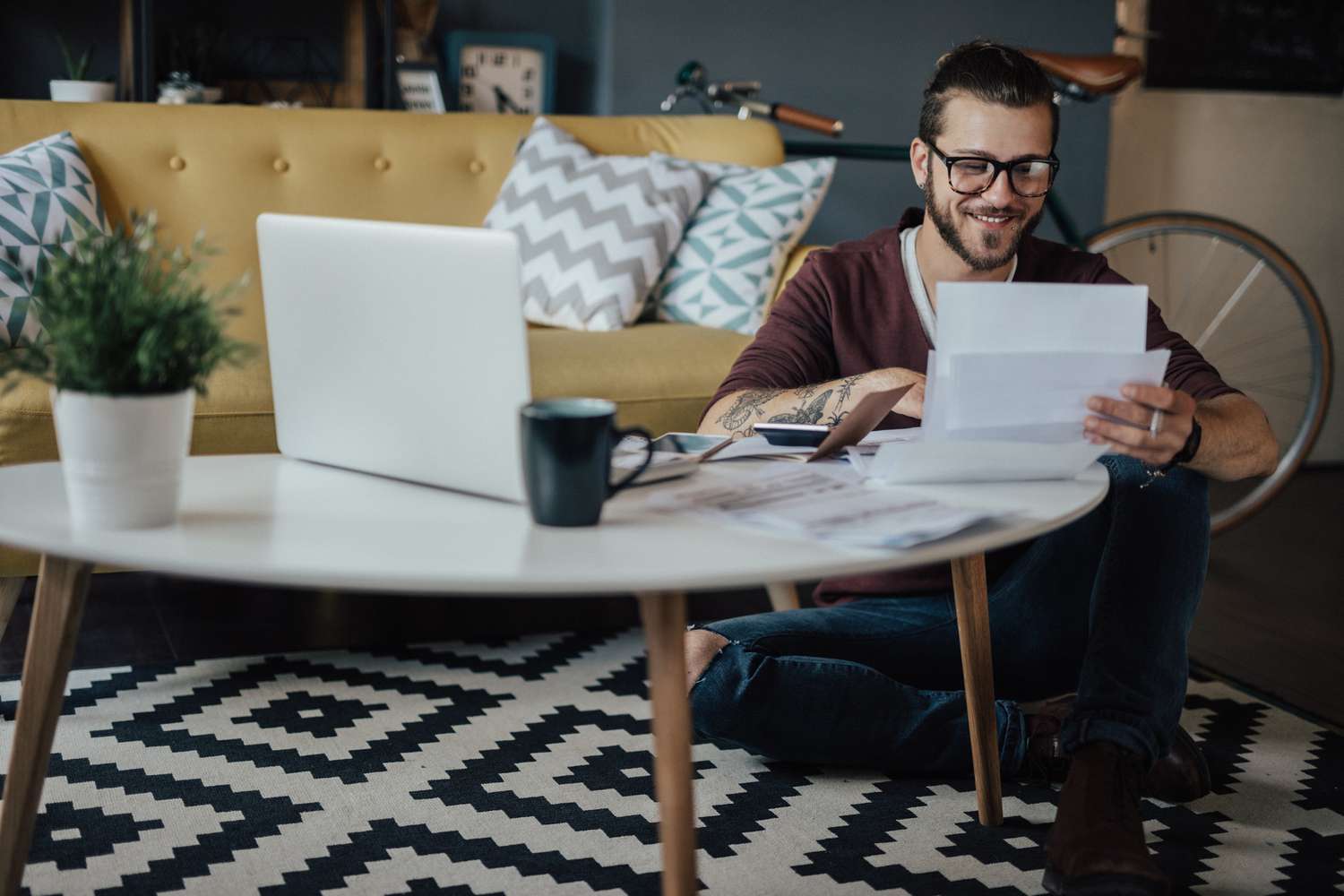 A person sitting on the floor smiling while reading documents for a second-chance bank account.